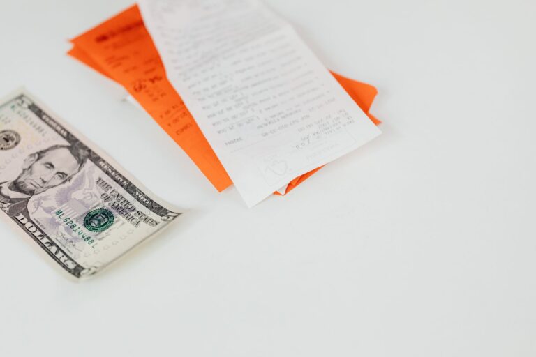 A five-dollar bill beside paper bills and receipts
