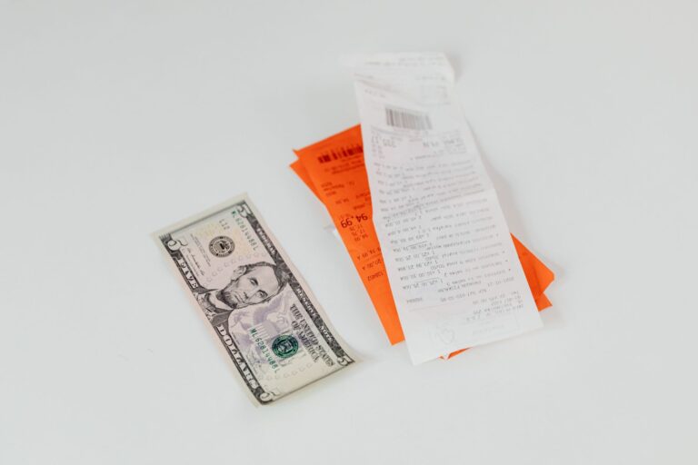 A five-dollar bill beside shopping receipts on a white background